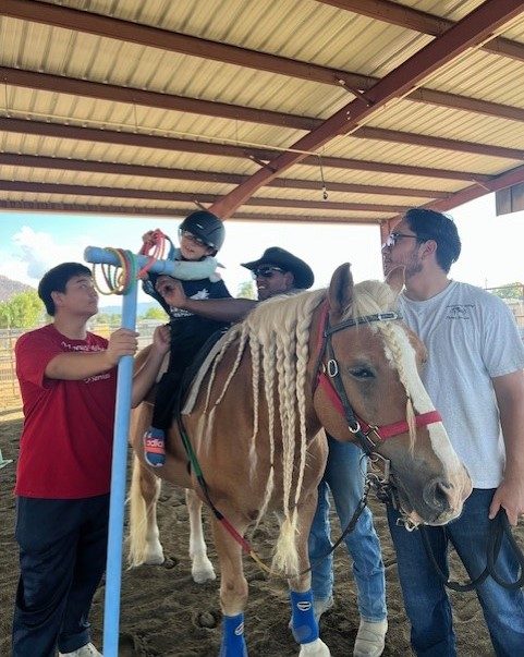 Volunteers supporting a rider on horseback in the covered arena