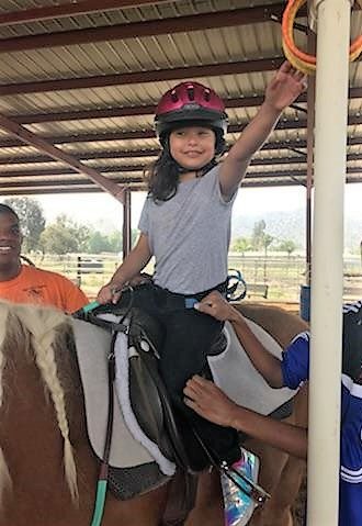 A young rider reaching up to place a ring on a pole during an arena game